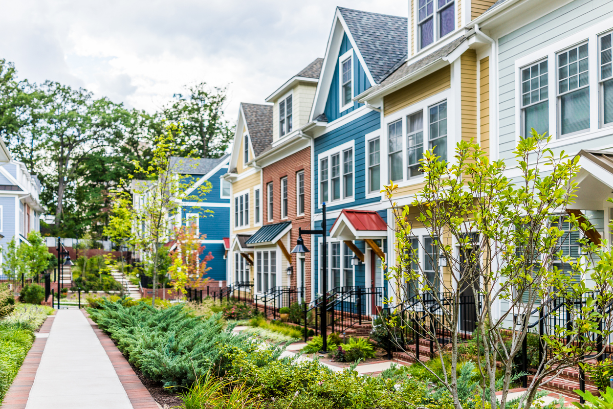 RentRedi press hero image: Row of colorful, red, yellow, blue, white, green painted residential townhouses, homes, houses with brick patio gardens in summer