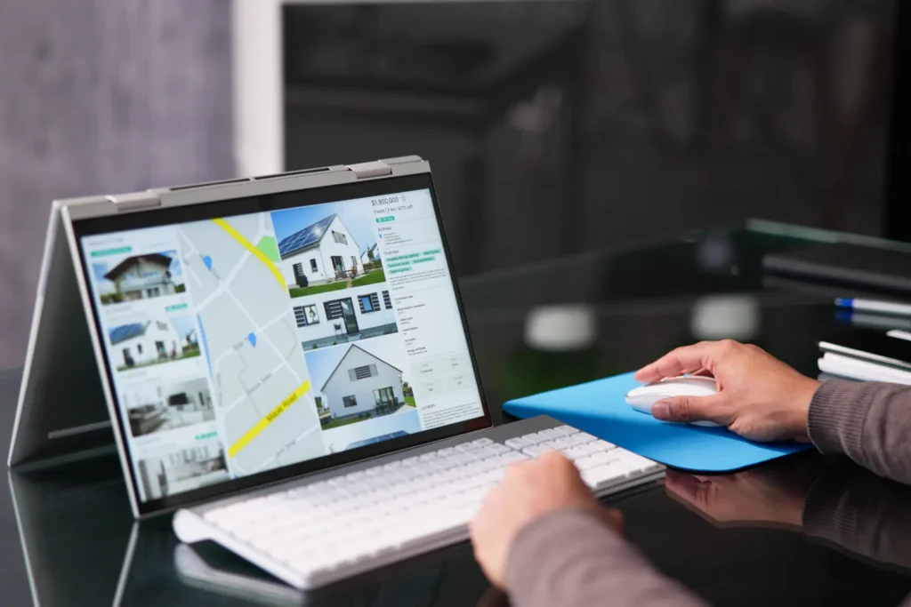 Property management computer software showing property listings and map view on a touchscreen laptop.