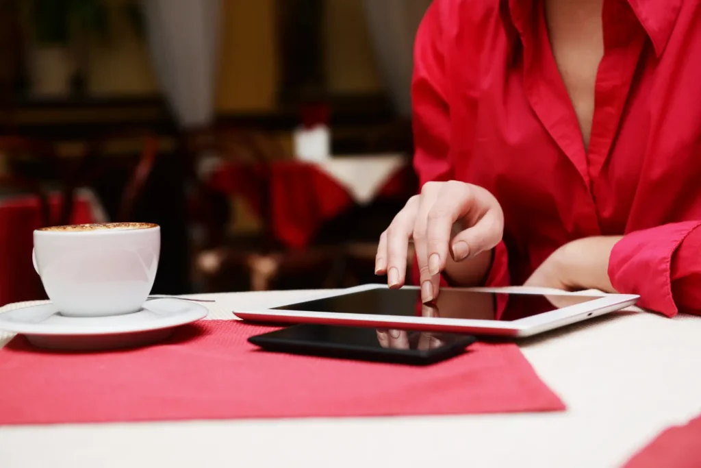 Property management software for landlords being used on a tablet at a café beside a cup of coffee.