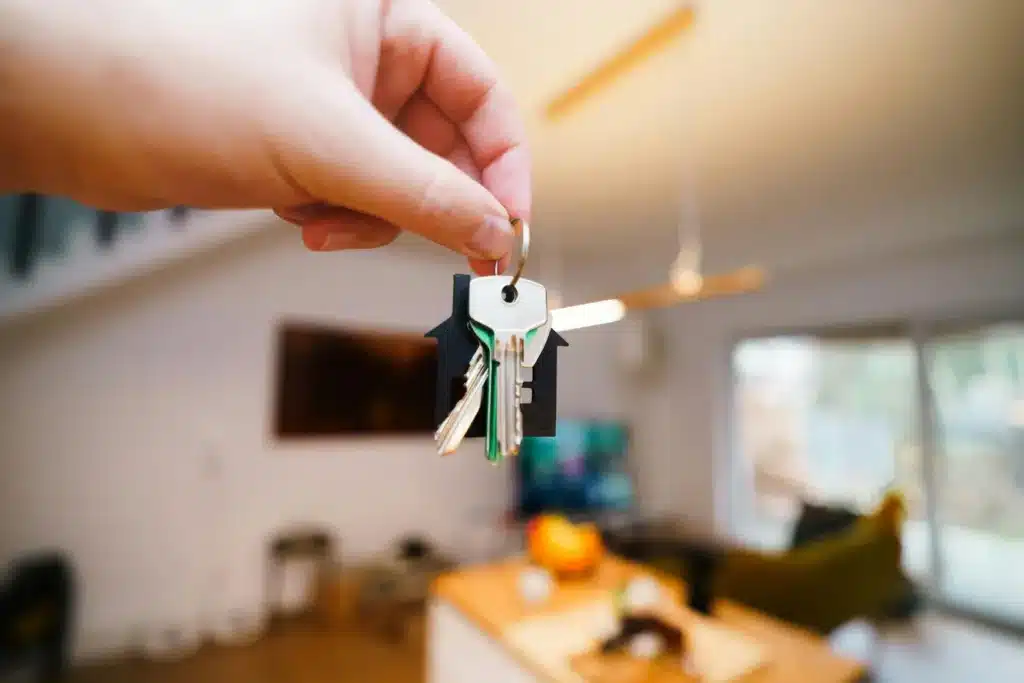 Rental qualifications symbolized by a hand holding house-shaped keys inside a modern home.