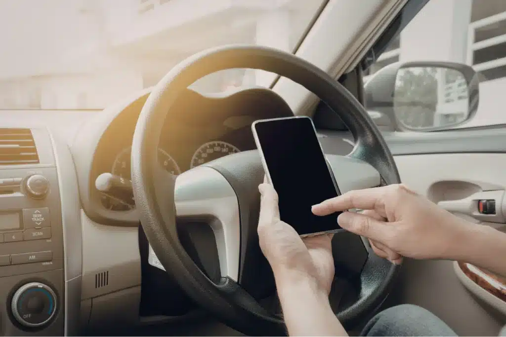 Property management app accessed on smartphone inside car, enabling landlords to manage rentals on the go.