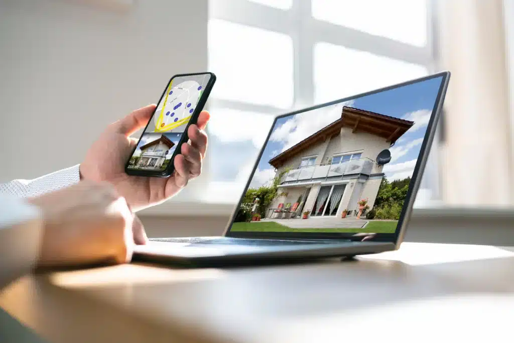 Property management software features shown through multi-device workflow—smartphone map view and laptop displaying a property exterior.