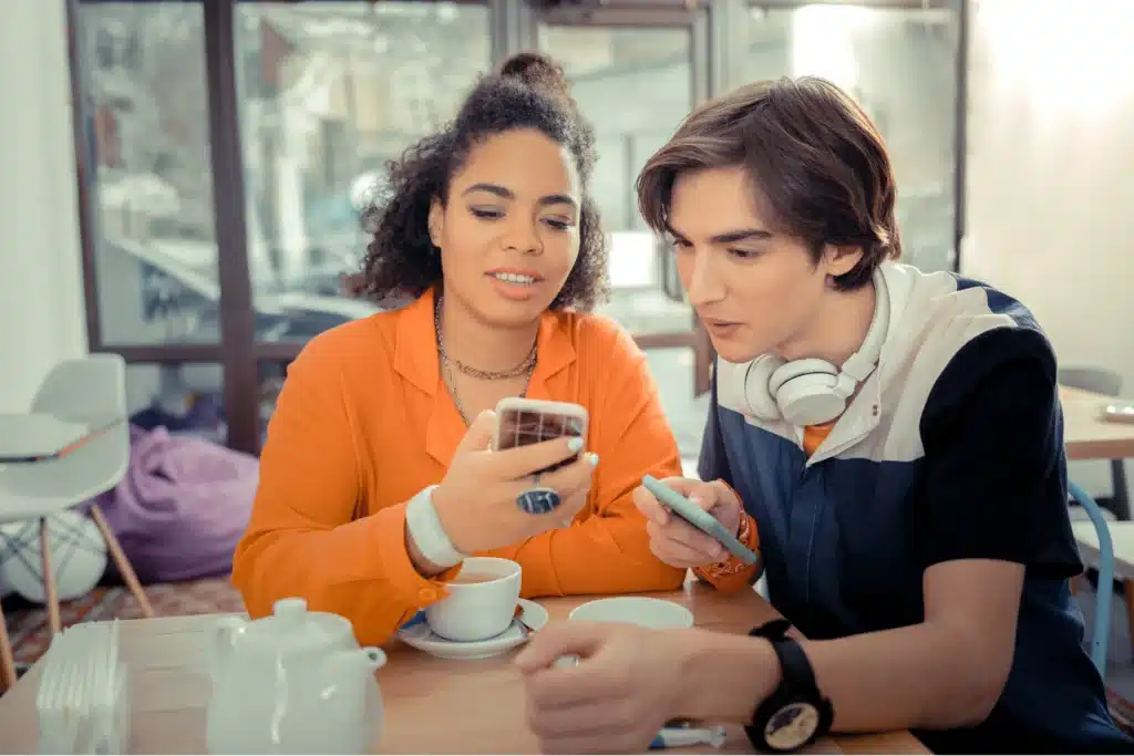 Best landlord app illustrated by two renters reviewing property details together on a smartphone at a café.