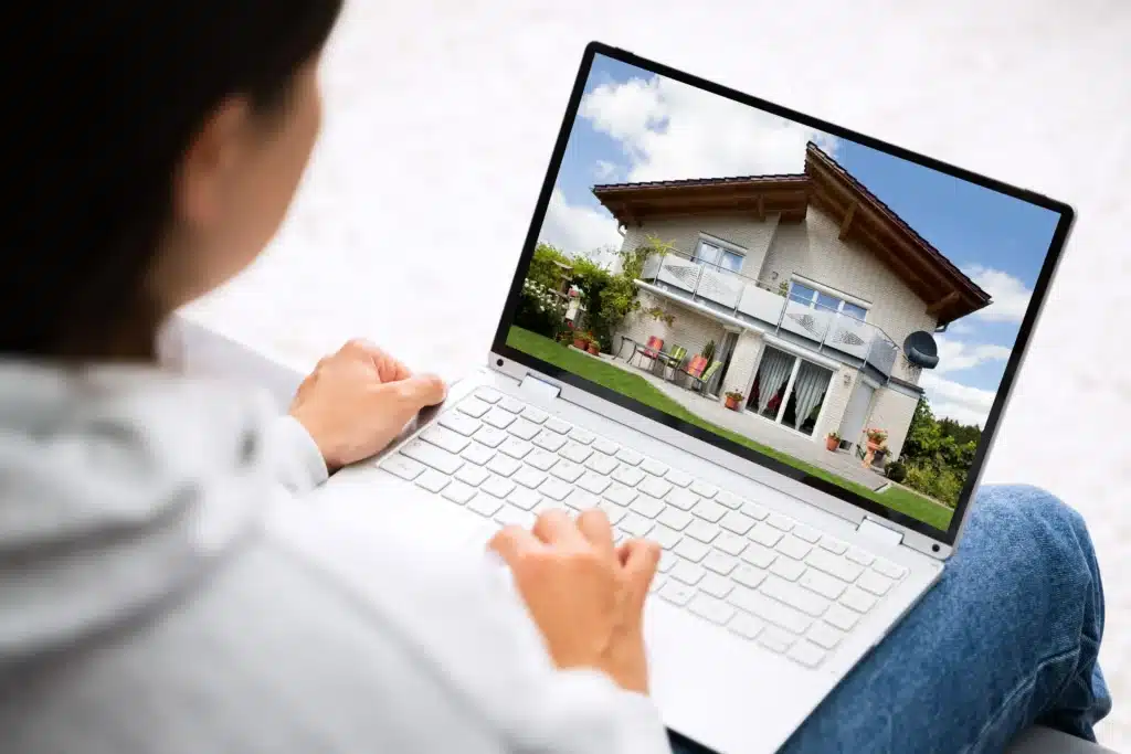 renter views a home exterior on a laptop screen, managing property details and maintenance online.