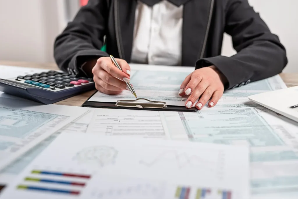 Real estate tax deductions being calculated by a professional filling out IRS tax forms on a clipboard surrounded by financial documents and a calculator