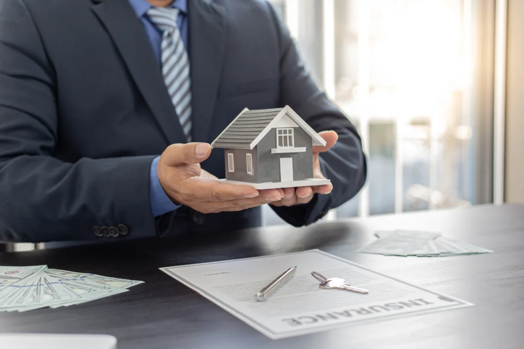 Rental property accounting depicted by a broker holding a house model over a signed contract and keys.