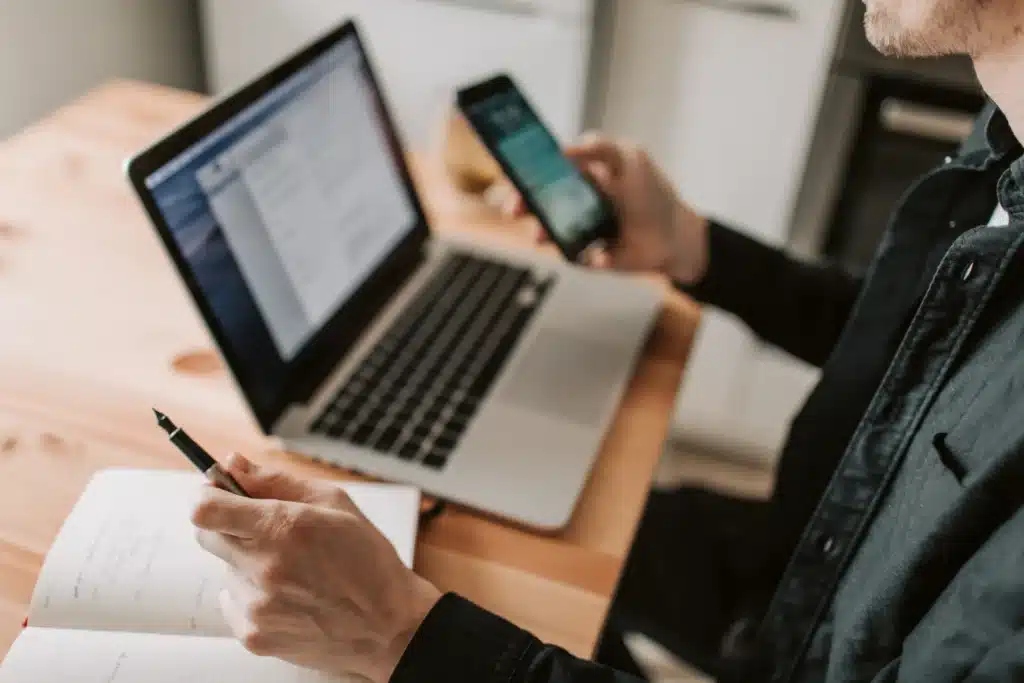 man using preventive maintenance solutions on laptop and smartphone with notepad on desk