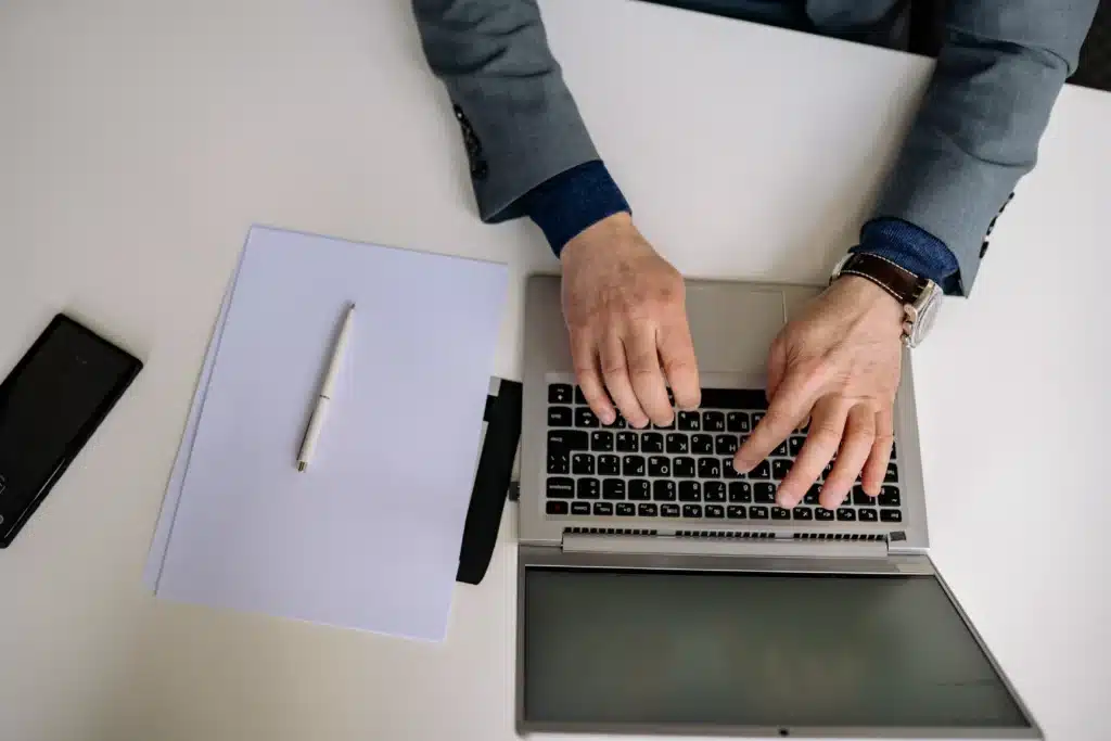 businessman using property management applications on laptop with documents on desk