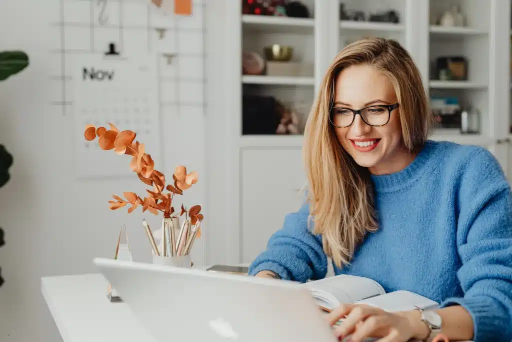 smiling woman using property management system software on laptop at her home office