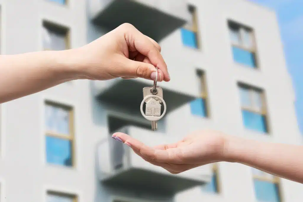 landlord handing over keys to tenant in front of apartment building for real estate maintenance
