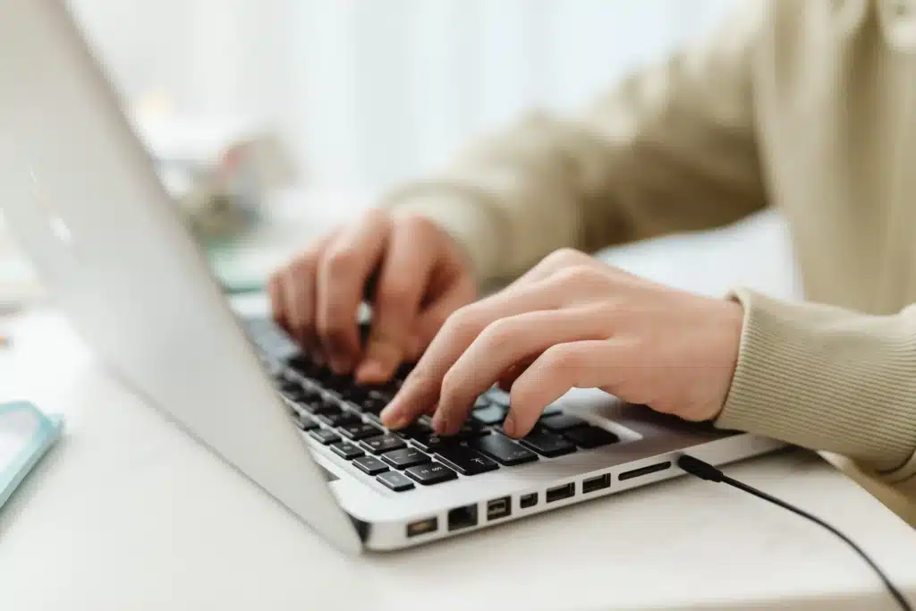 hands typing on laptop using real estate property management software at a desk