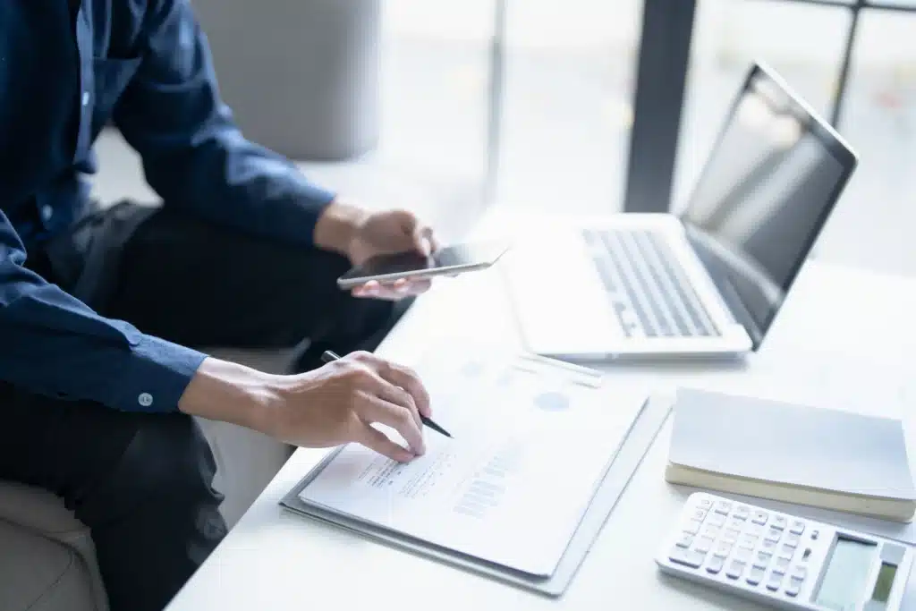 property manager reviewing real property management software reports on laptop and smartphone at desk