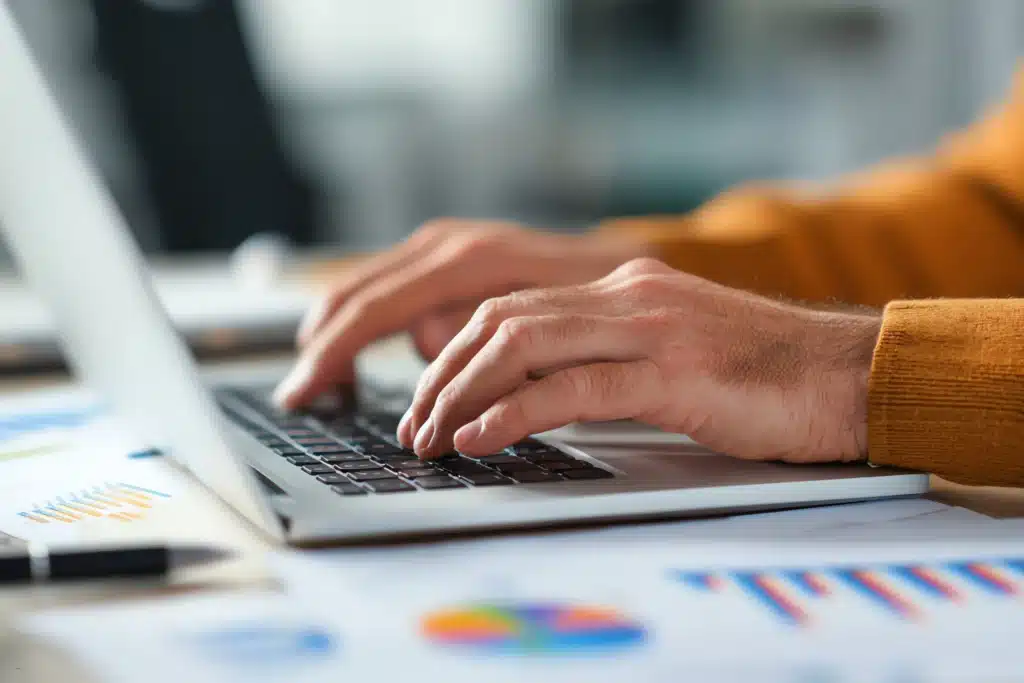 person working on rental property maintenance software with financial charts and reports on desk