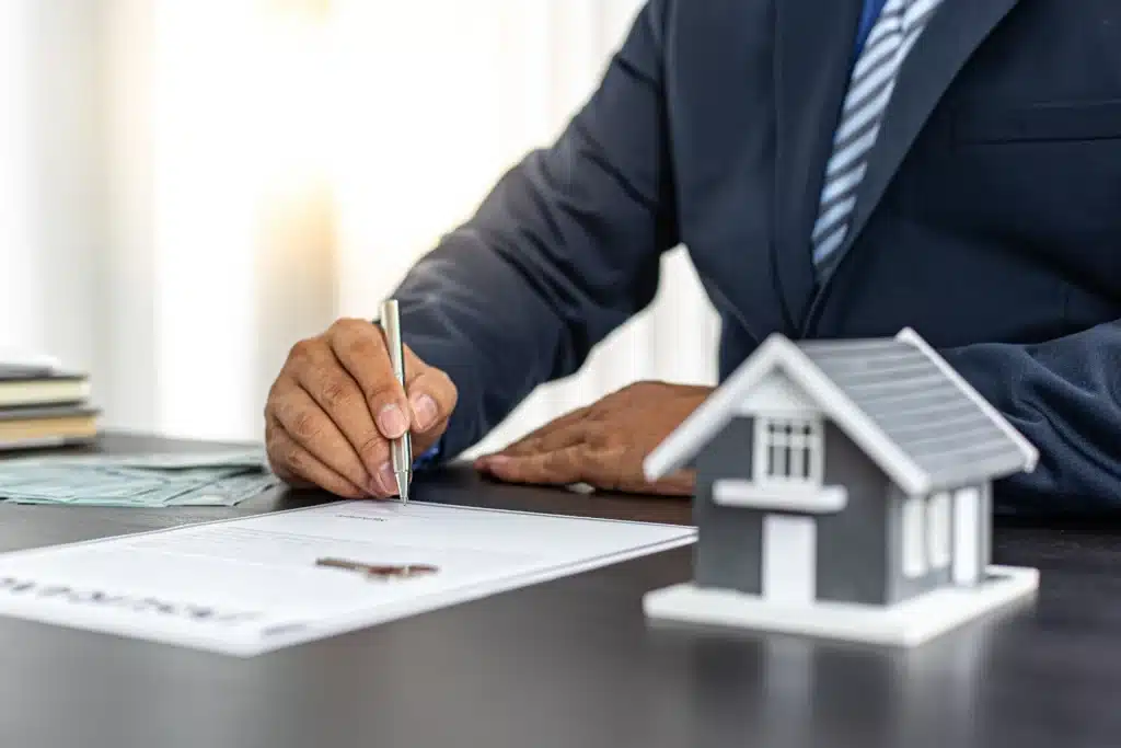 businessman signing a rental property management agreement with house model on desk